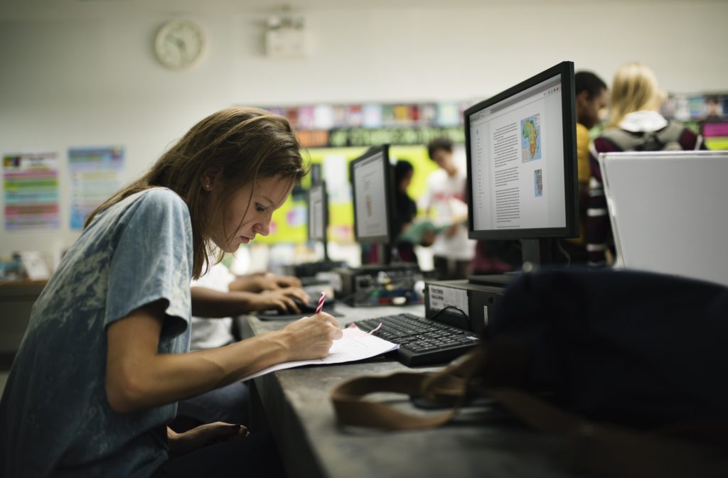 Caucasian woman writing at computer room