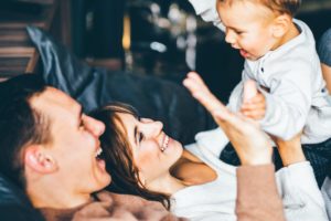 Young parents and cute baby lying together. Young parents hugging and smile.
