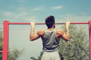 young man exercising on horizontal bar outdoors