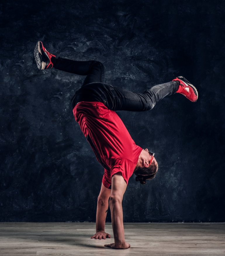 Hip-hop style dancer performs breakdance acrobatic elements.