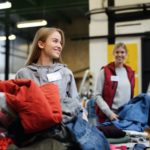 Volunteers sorting out donated clothes in community charity donation center.