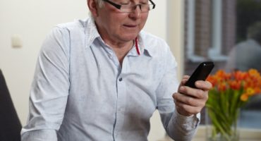Senior man at home texting on mobile phone