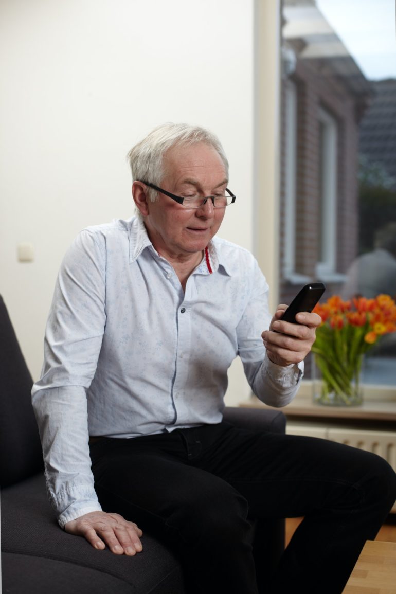Senior man at home texting on mobile phone