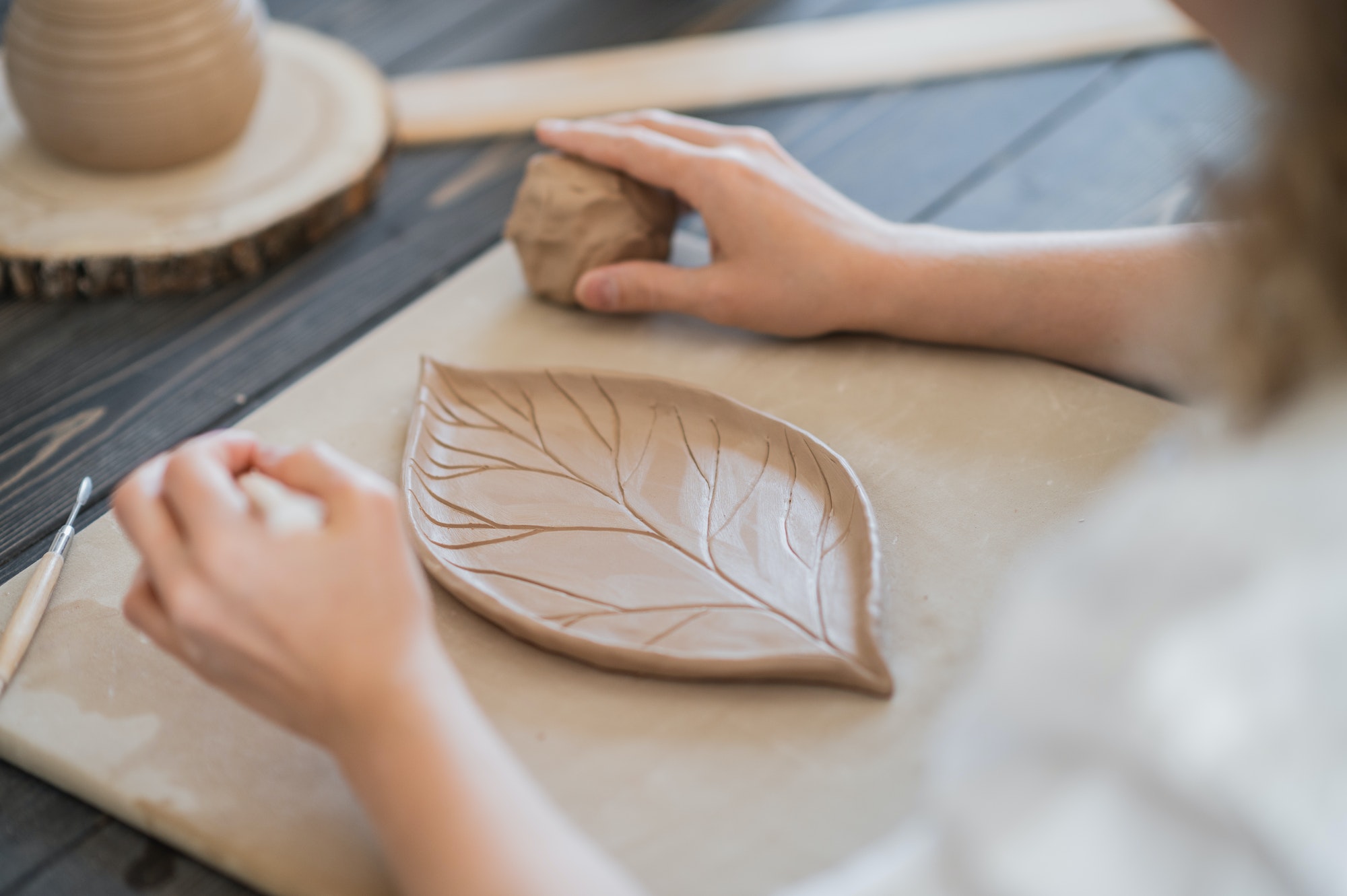 Woman decorating handmade pottery plate close-up